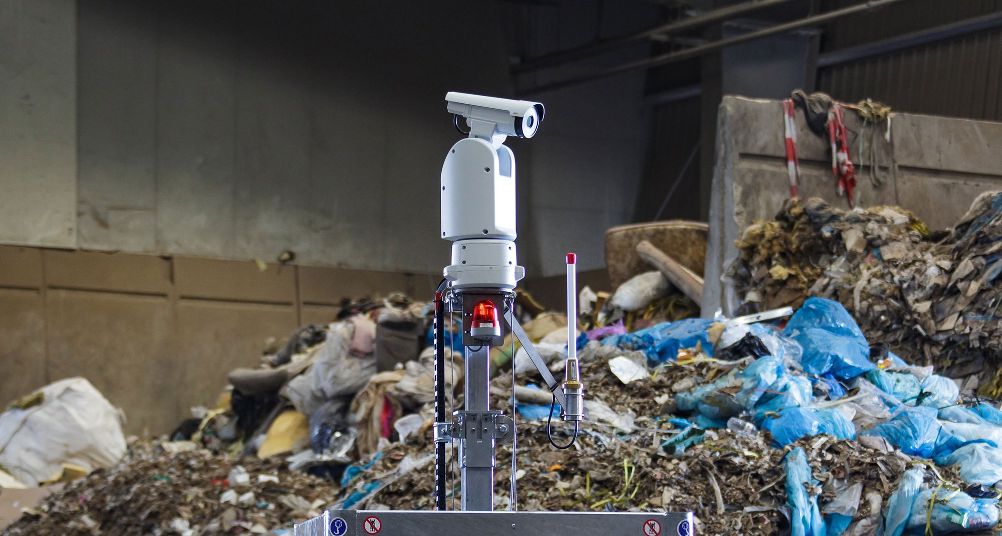 The Kooi RED thermometric camera system positioned in a waste management facility, monitoring heaps of recyclable materials to ensure early detection of fire risks and operational safety.
