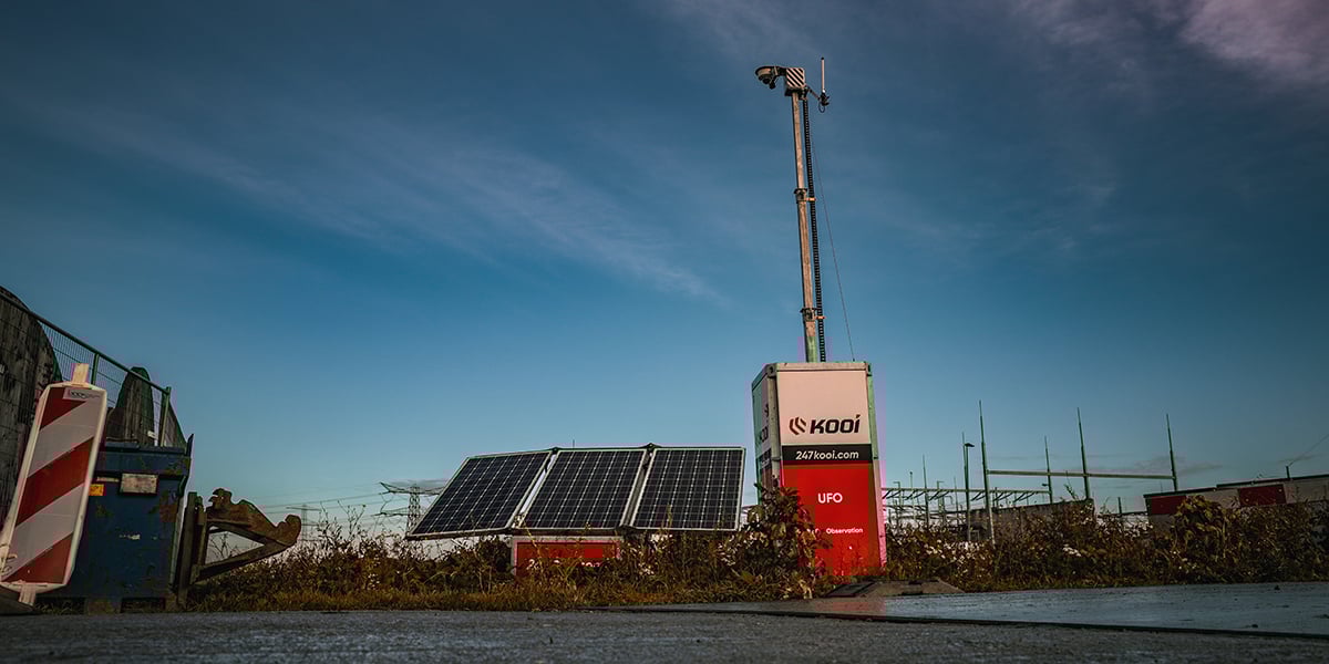 Kooi UFO security unit protecting a construction site at sunset, with wind turbines in the distance, highlighting reliable, innovative, and sustainable site monitoring solutions.