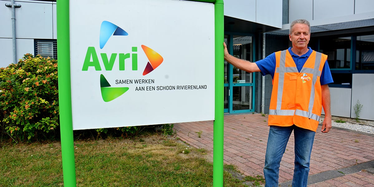 A worker in a high-visibility vest standing next to the Avri sign, representing collaboration and commitment to a cleaner environment in the Netherlands.